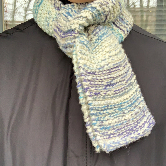 A blue & white variegated scarf is wrapped around someones neck and thread through itself