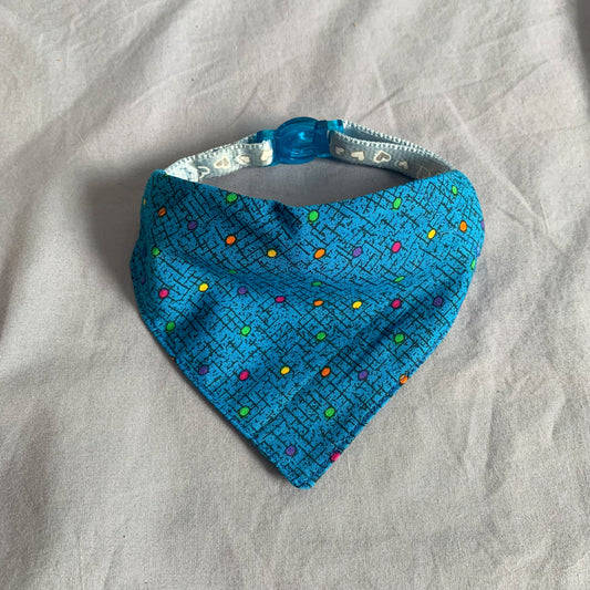a blue dotted triangle cat bandana on a blue collar sat on a blue background