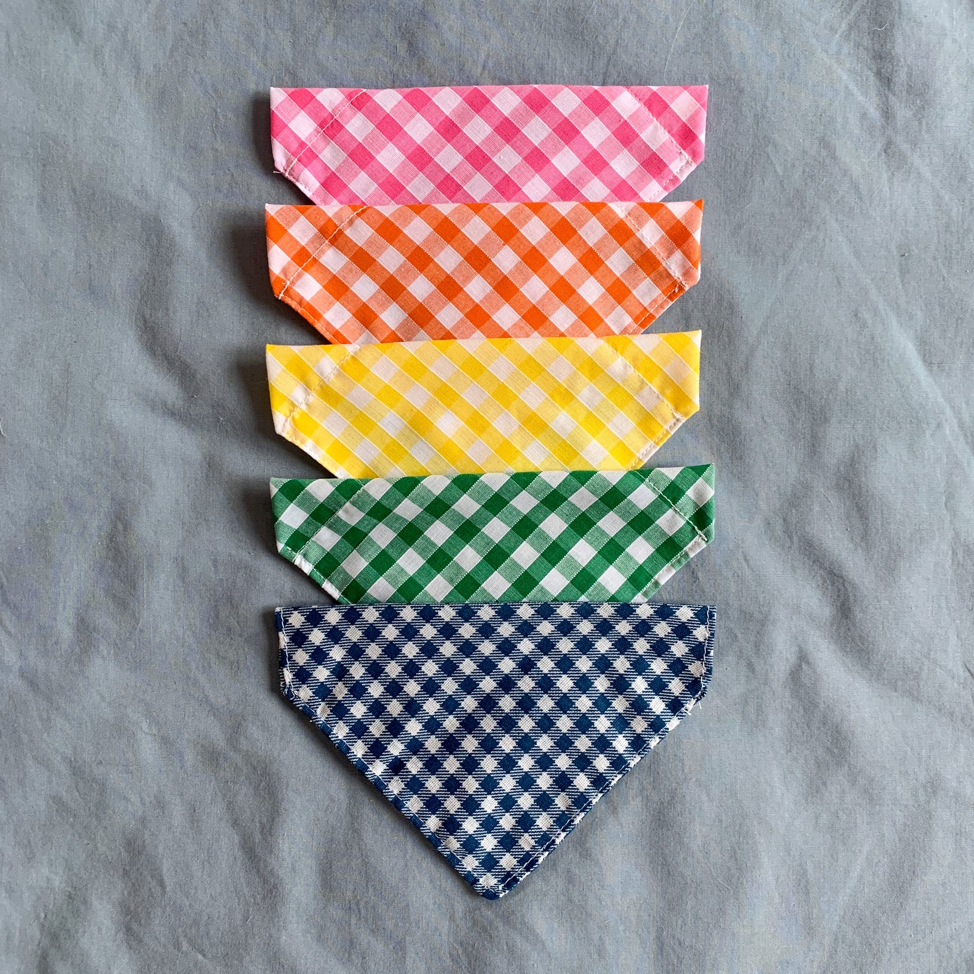 triangle gingham pet bandanas in a line, pink, orange, yellow, green and blue