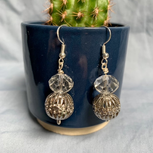 Shiny ball stacked earrings hang off a dark blue cactus pot