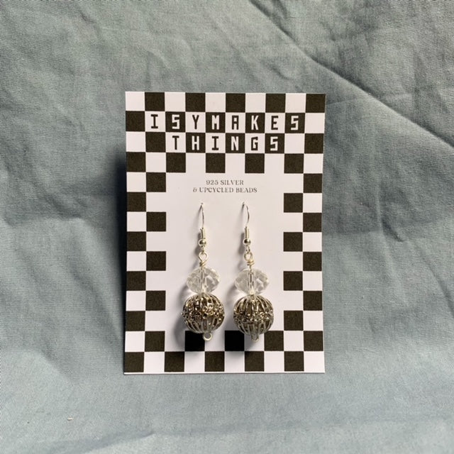 Shiny ball stacked earrings hang off a black and white checkered backing card with the title isymakesthings