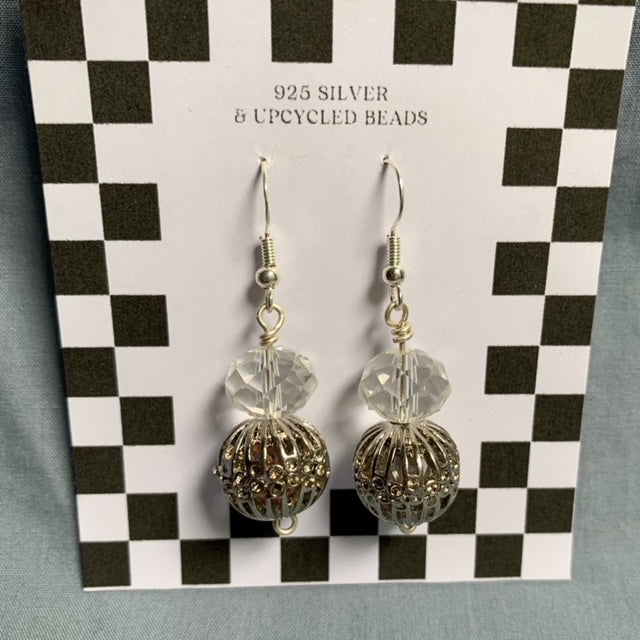 Shiny ball stacked earrings hang off a black and white checkered backing card with the title isymakesthings