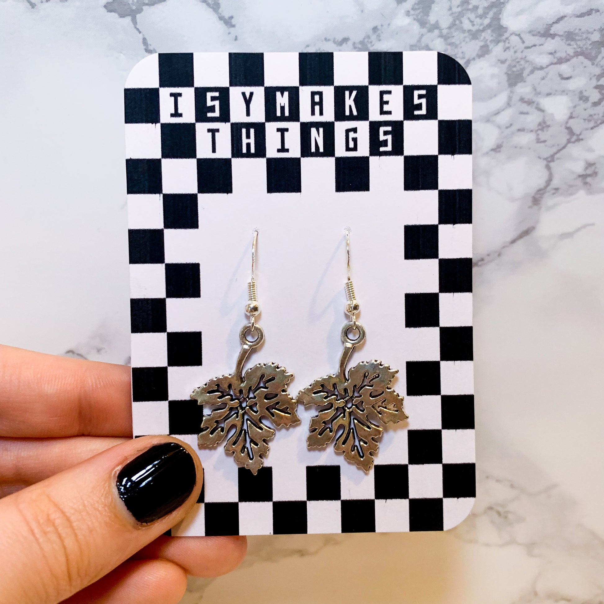 Silver leaf dangle earrings on a black and white checkered backing card with the title isymakesthings