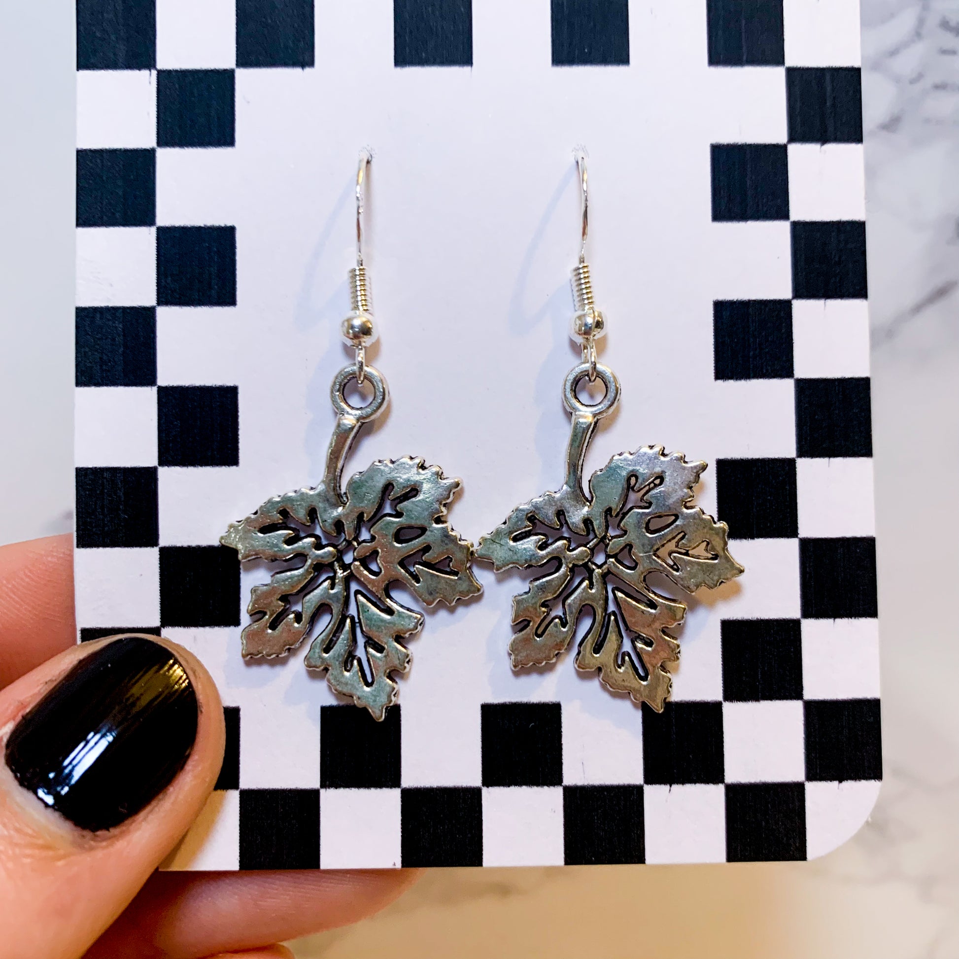 Silver leaf dangle earrings on a black and white checkered backing card with the title isymakesthings