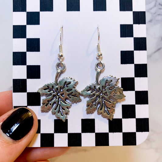 Silver leaf dangle earrings on a black and white checkered backing card with the title isymakesthings