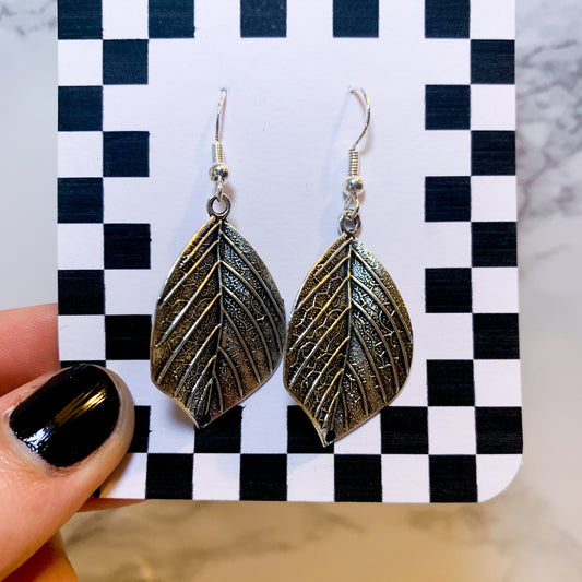 Silver leaf dangle earrings on a black and white checkered backing card with the title isymakesthings