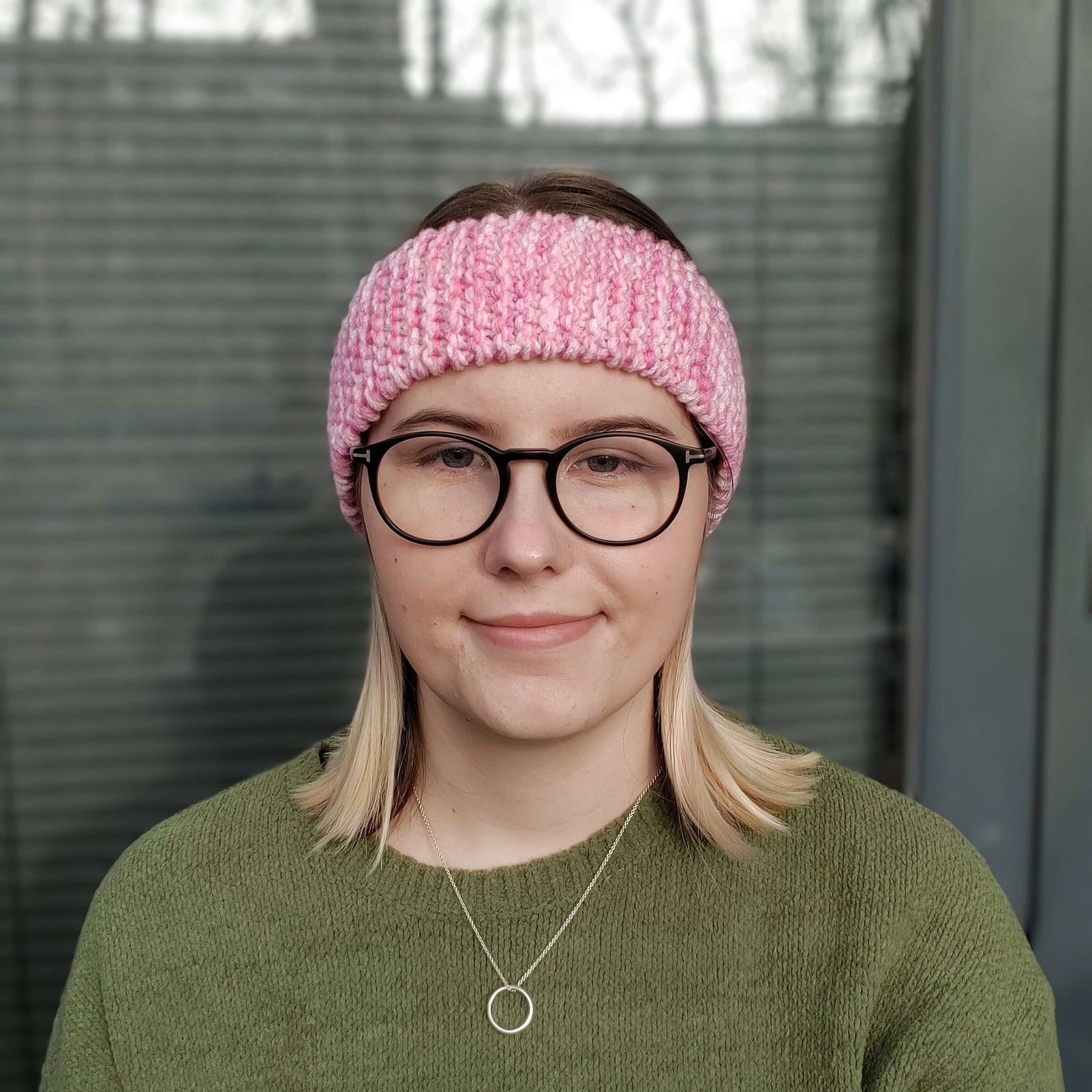 A woman models a pink variegated knitted headband ear warmer