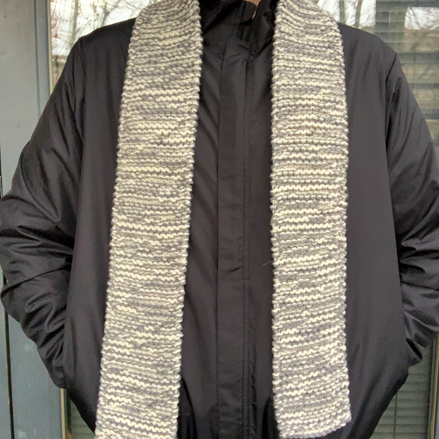 A grey & white variegated scarf is laid around a persons neck