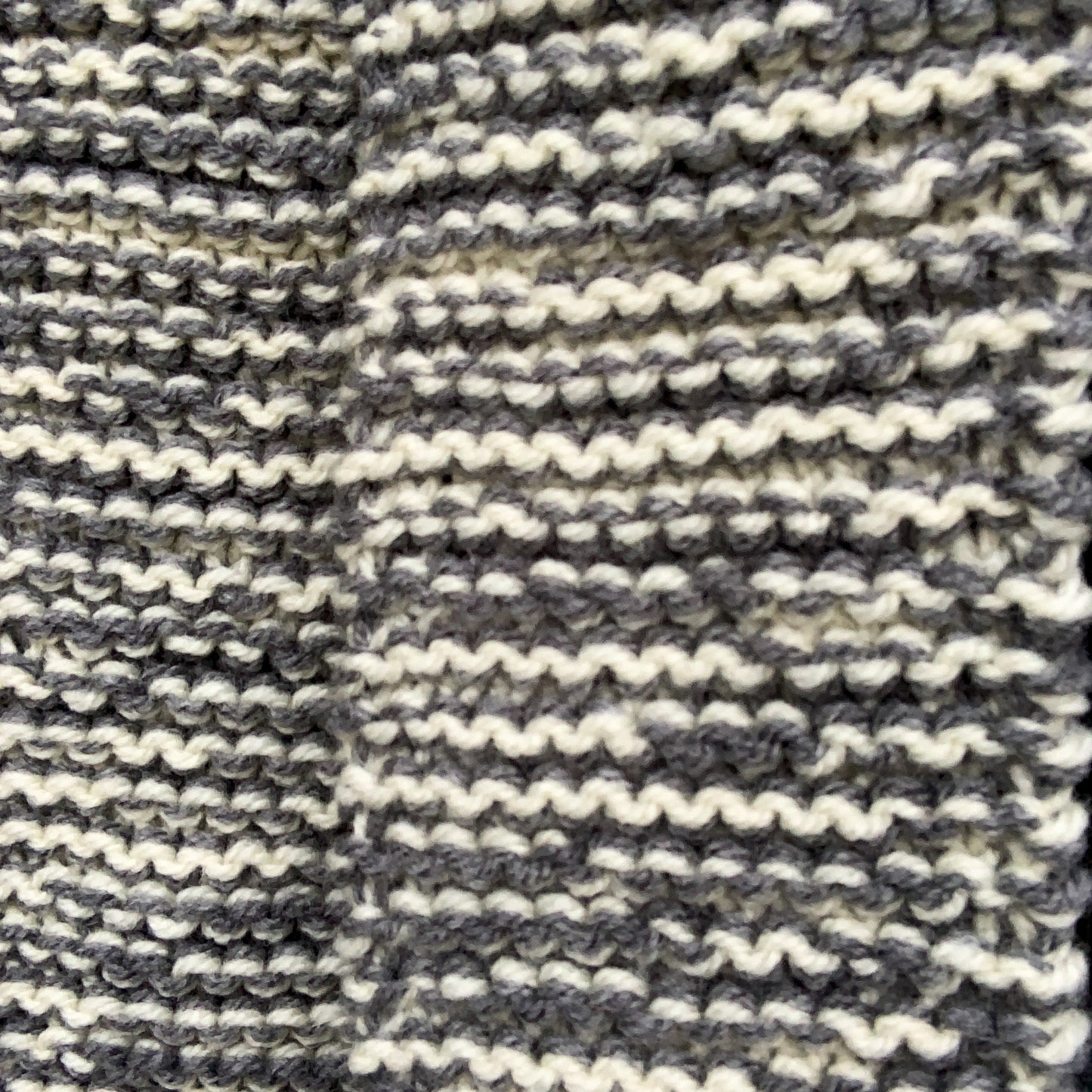 A close up of a grey & white variegated knitted scarf