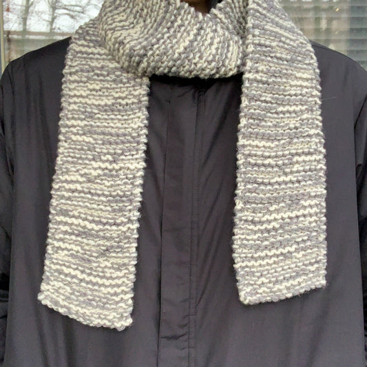 A grey & white variegated scarf is wrapped round a persons neck