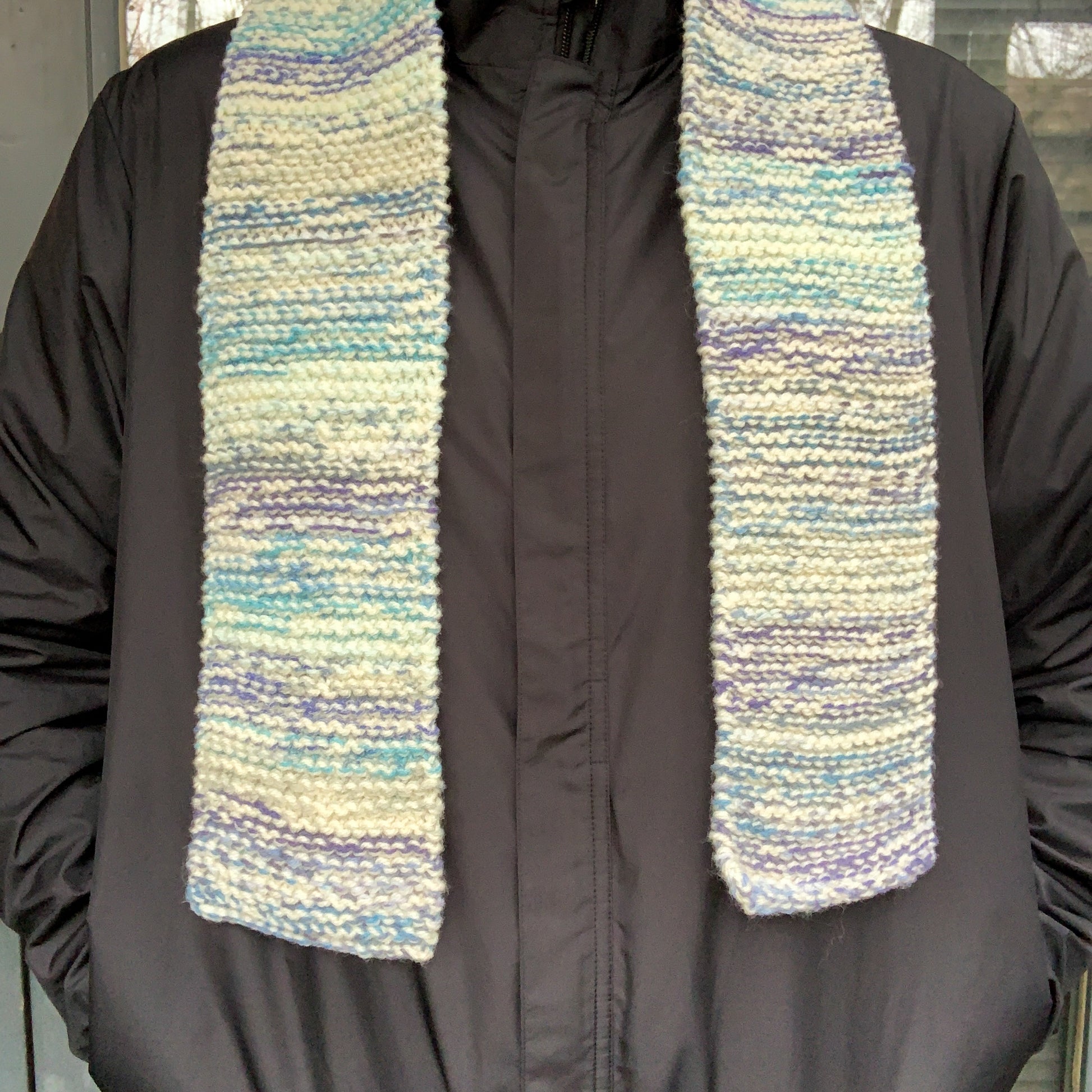 A blue & white gradient variegated scarf is laid across a persons shoulders and hangs down their front