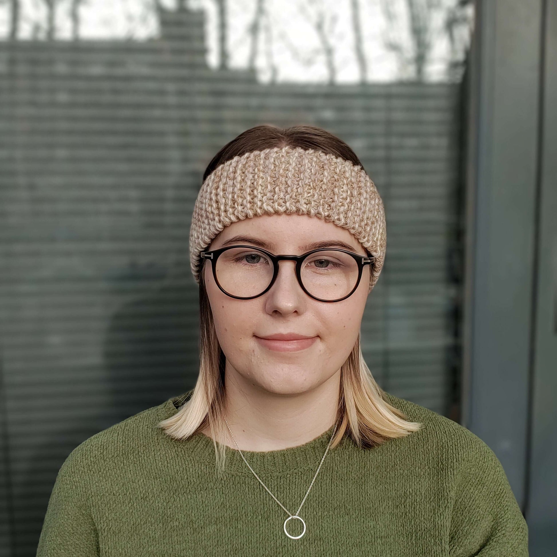 A woman models a beige variegated ear warmer knitted headband