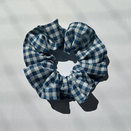 A blue gingham scrunchie on a white background.