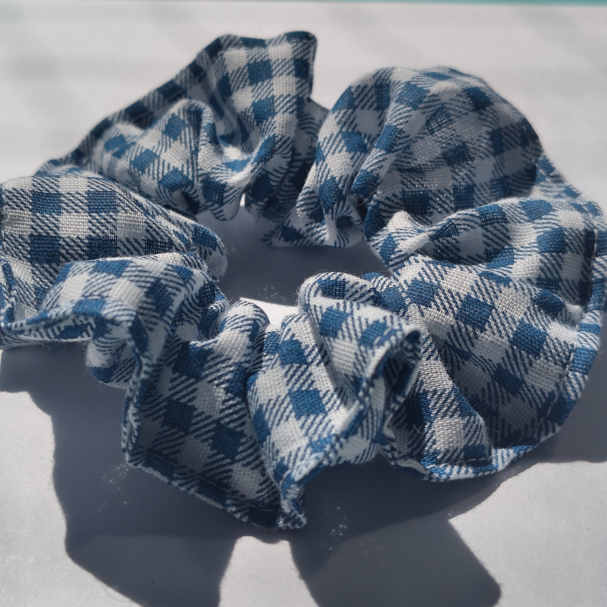 A closeup of a blue gingham scrunchie.