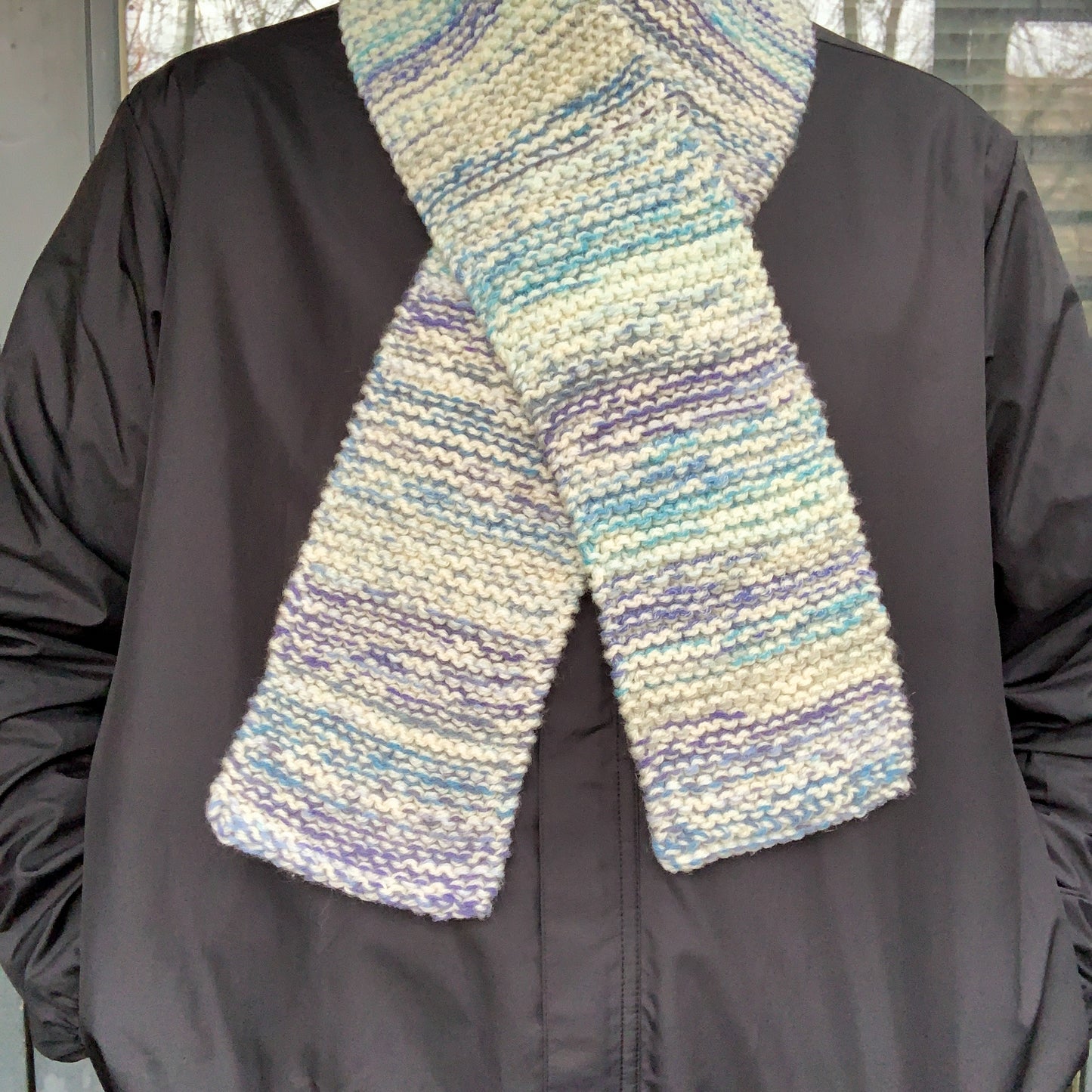 A blue & white gradient variegated scarf is crossed over the front of a person