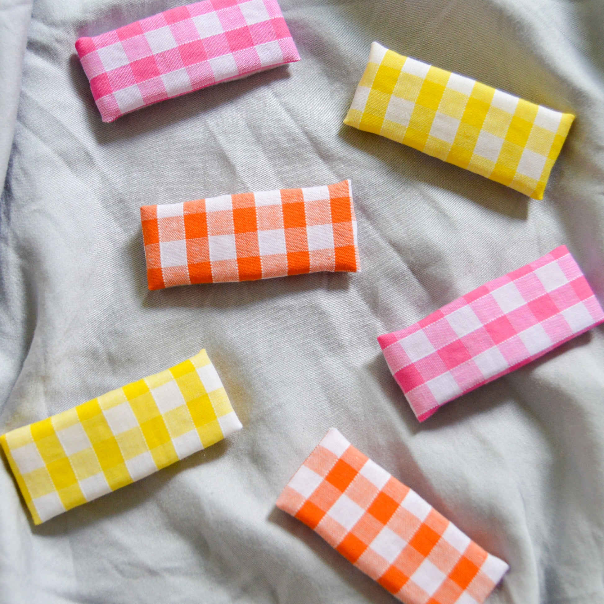 yellow orange and pink gingham hair clips are scattered about