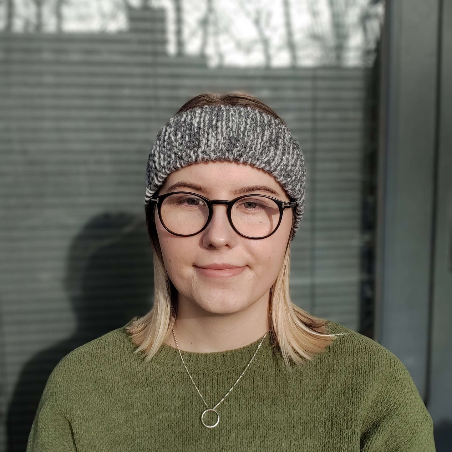 A woman models a grey variegated ear warmer knitted headband