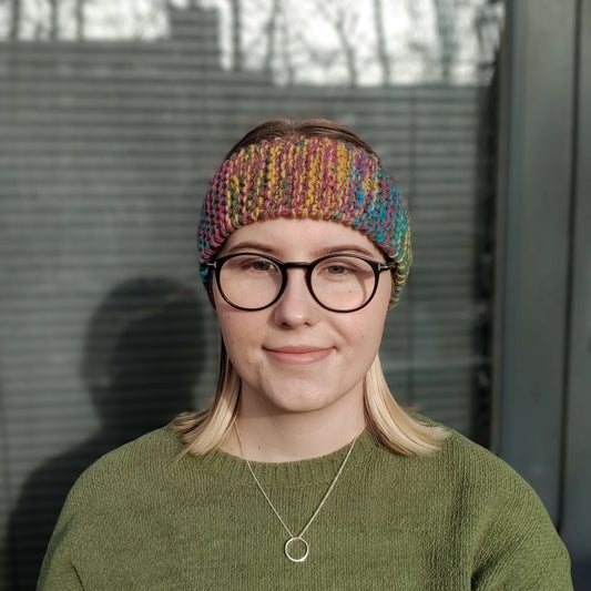 A woman models a multicolour knitted ear warmer headband