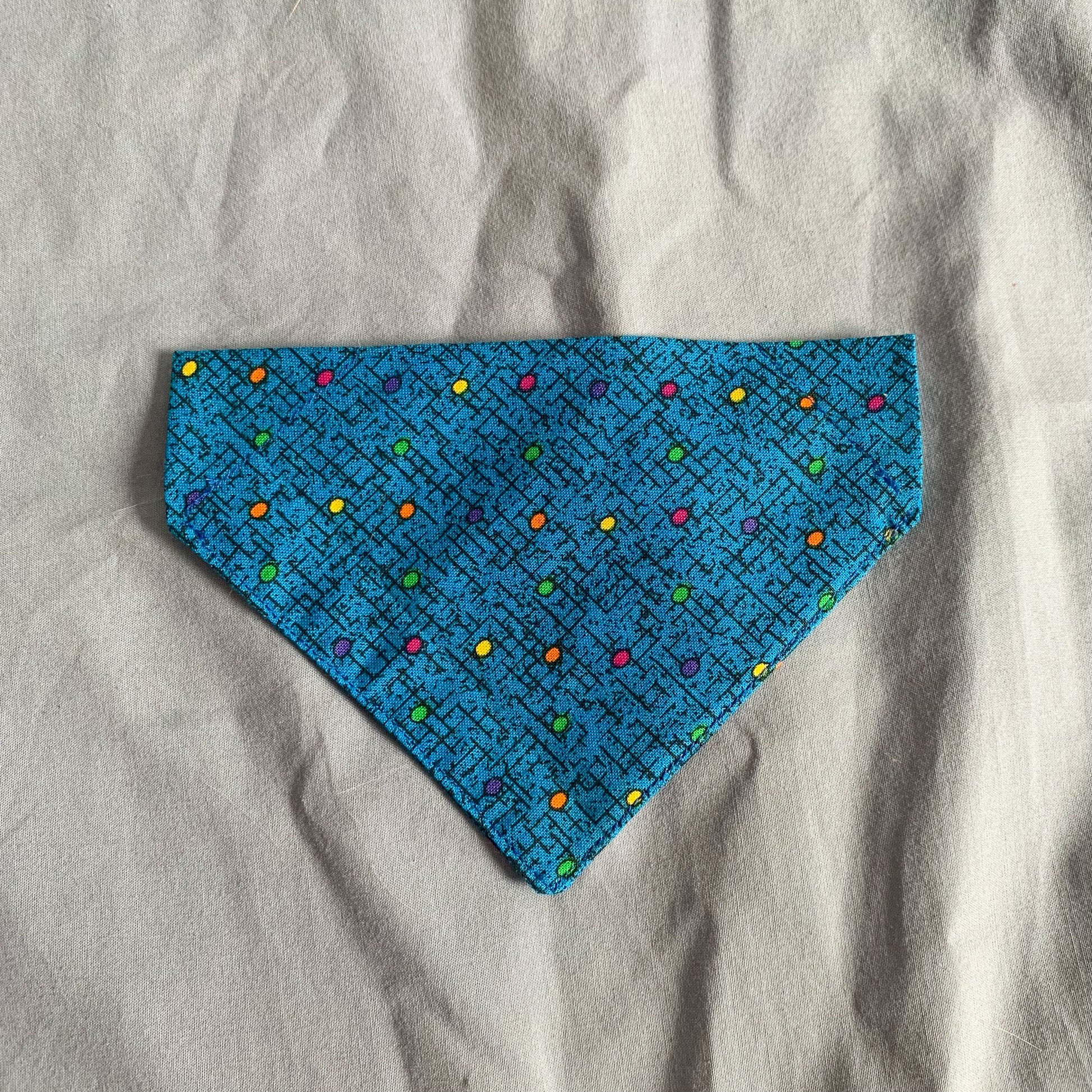 a blue dotted triangle cat bandana laying on a blue background