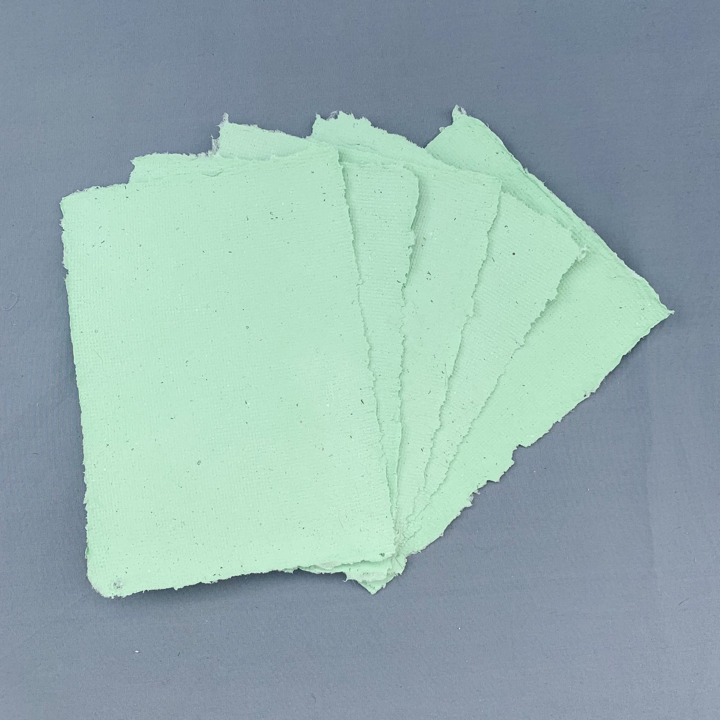 five fanned out sheets of green paper across a blue background