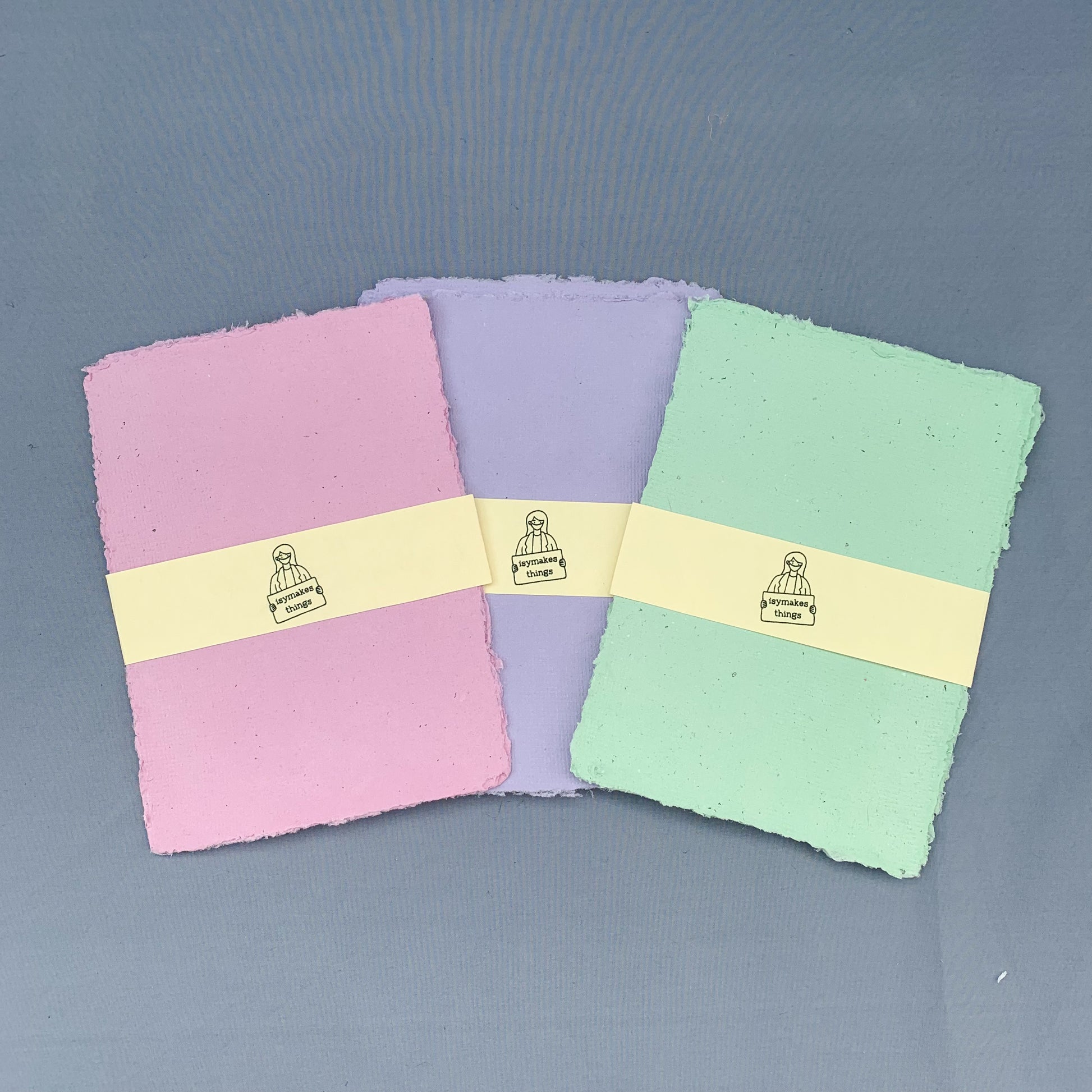 stacks of pink, purple and green paper fanned across a blue background