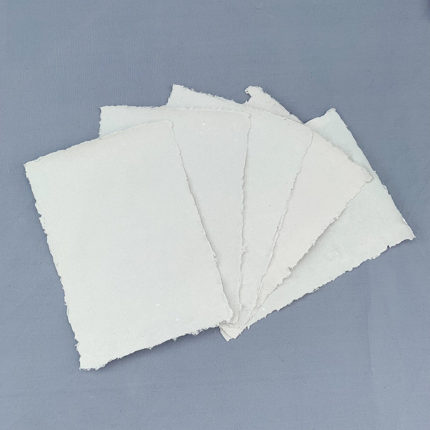 five fanned out sheets of grey paper across a blue background