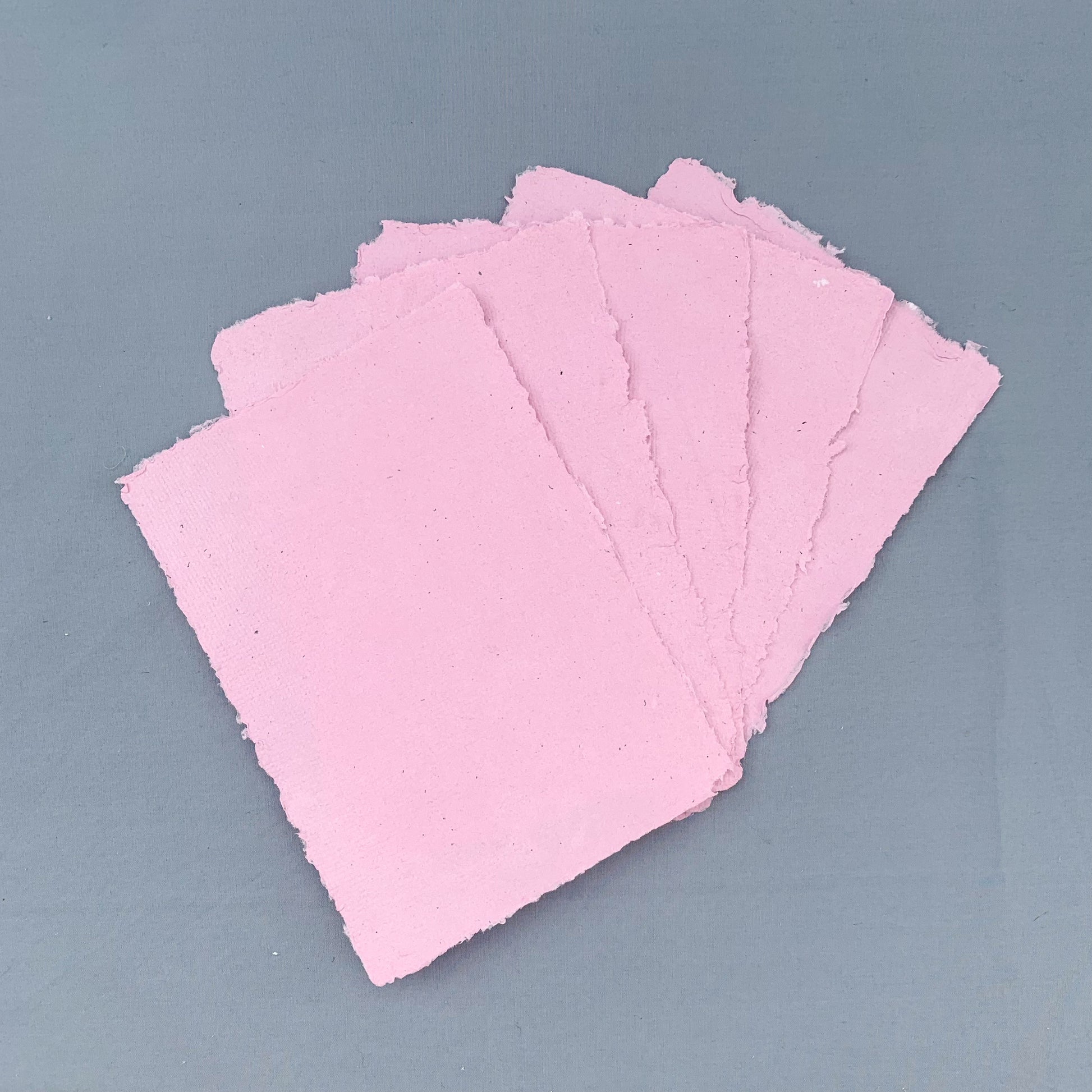 five fanned out sheets of pink paper across a blue background