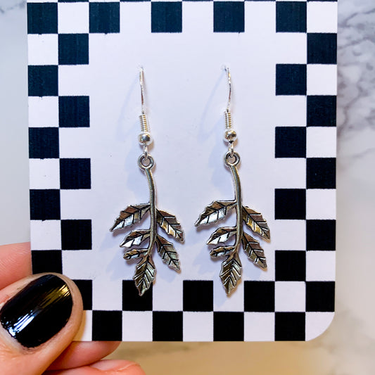 Silver leaf dangle earrings on a black and white checkered backing card with the title isymakesthings