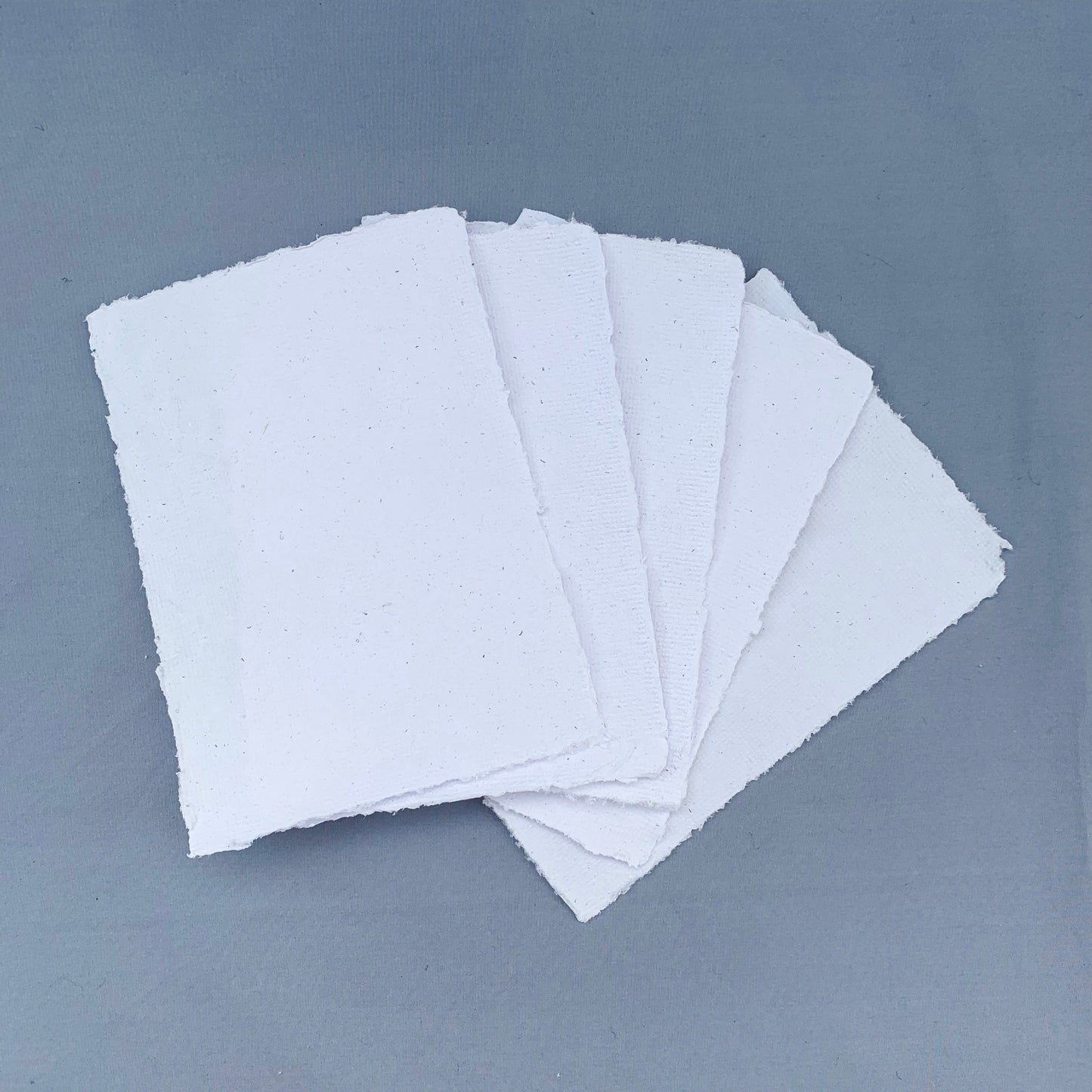 five fanned out sheets of white paper across a blue background